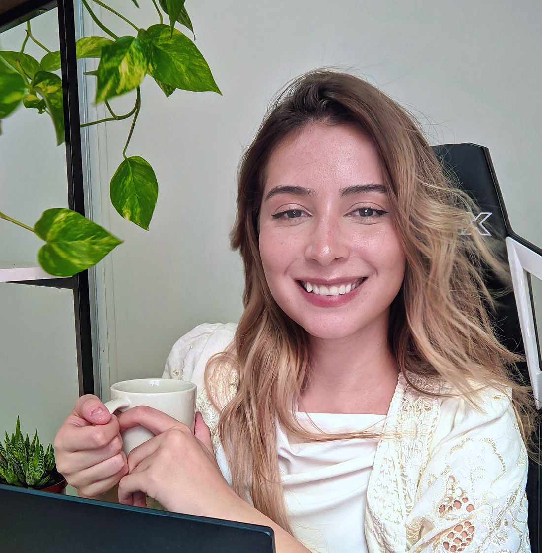 Vitória Alves, psicóloga, sorrindo em sua mesa de atendimento online